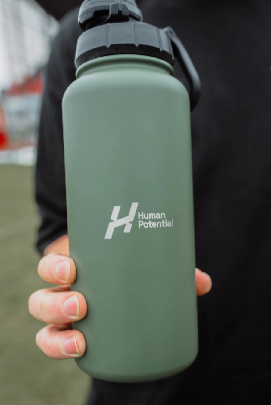 Green water bottle with 'Human Potential' logo held by a person